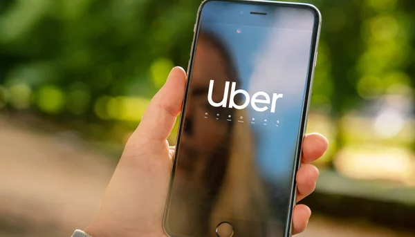 Uber driver holder smartphone i bilen. Uber er et amerikansk selskab. - Stock-foto