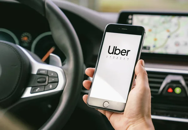 Uber driver holding smartphone in car. Uber is an American compa — Stock Photo, Image