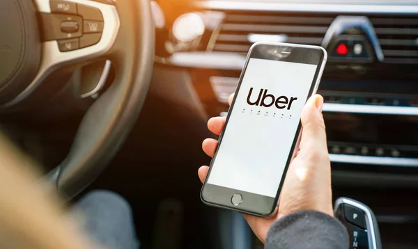 Uber driver holding smartphone in car. Uber is an American compa — Stock Photo, Image