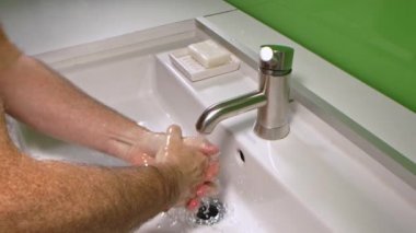 Virüs enfeksiyonunu önlemek için ellerini yıkayan bir adam.
