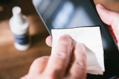 Temiz akıllı telefon için dezenfekte mendilleri olan cep telefonu ekranını temizleyen kişi. COVID-19 Coronavirüs Salgın Önleme Konsepti.