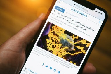 Bilim Haberleri web sitesinin içeriğiyle elmalı iphone ekranı Coronavirus of the corona covid-19 virüsünün elektron mikrografını gösteriyor