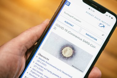 Elma iPhone ekranı RKI 'nin içeriğiyle Coronavirus of Corona covid-19 virüsünün elektron mikrografını gösteriyor.