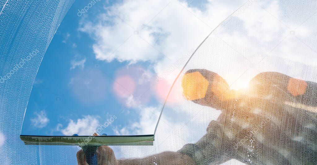 window cleaner cleaning window with squeegee and wiper on a sunny day