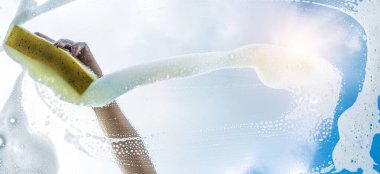 Güneşli bir günde cam sileceği ve silecekle pencere temizleyicisi