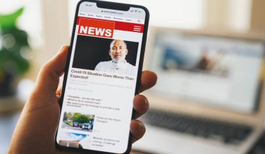 Akıllı bir telefondan online haberler. Bir cep telefonu ekran uygulamasındaki haberleri ya da makaleleri okuyan işadamlarına yakın durun. El ele tutuşan akıllı cihaz. Model web sitesi. Gazete ve internet portalı. Gösterilen haberler gerçekle ilgili değildir.