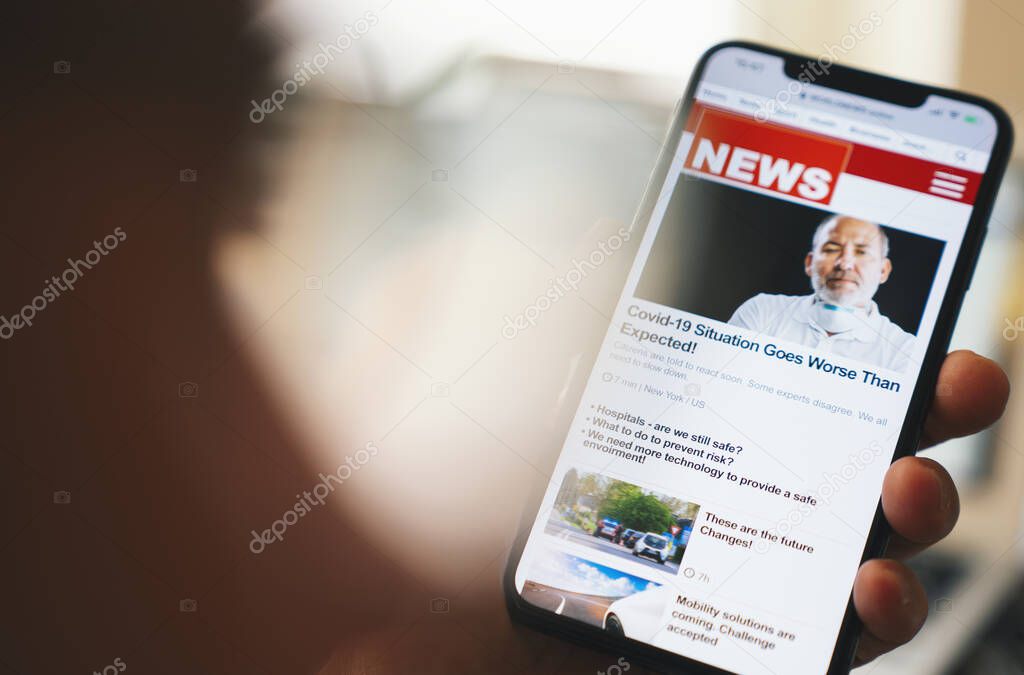 Online news on a smart phone. Close up of businessman reading news or articles in a mobile phone screen app. Hand holding smart device. Mockup website. Newspaper and portal on internet. Displayed news are not reality related
