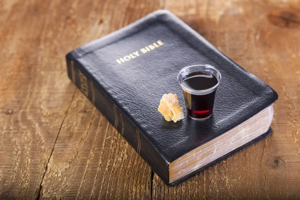 Taking Communion. Cup of glass with red wine and bread on Bible. — Stock Photo, Image