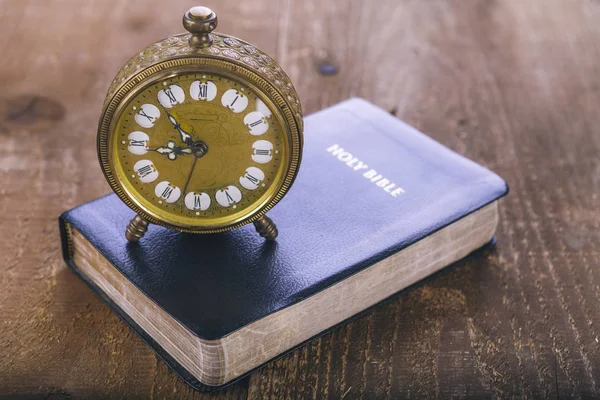 Heilige Bibel und alter Wecker auf Holztisch — Stockfoto