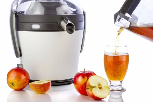 Juicer elétrico e suco de maçã derramando em vidro — Fotografia de Stock