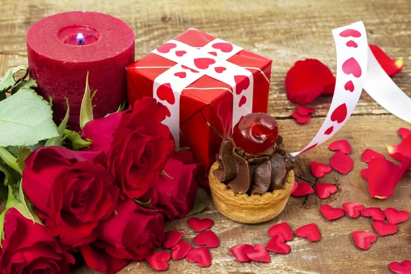 Cupcake with cherry in front of bouquet of red roses — Stock Photo, Image