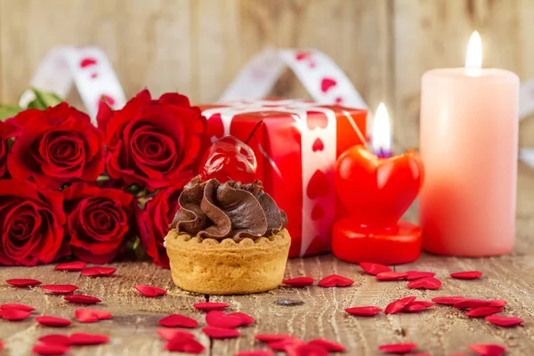 Cupcake with cherry in front of bouquet of red roses and cadles — Stock Photo, Image