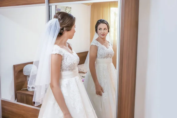 Novia en vestido blanco mirando en el espejo — Foto de Stock