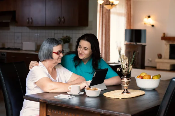 Pečující Zdravotní Sestra Ukazuje Digitální Tablet Starší Ženě Pečovatelském Domě — Stock fotografie