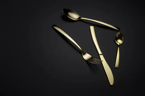Dos cucharas, cuchillo y tenedor sobre fondo oscuro Imágenes De Stock Sin Royalties Gratis