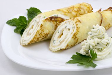 Nane ile beyaz bir plaka üzerinde peynir soslu krep bırakır