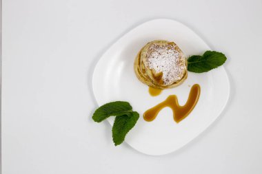 Krep ile bal ve nane yaprakları beyaz bir plaka üzerinde