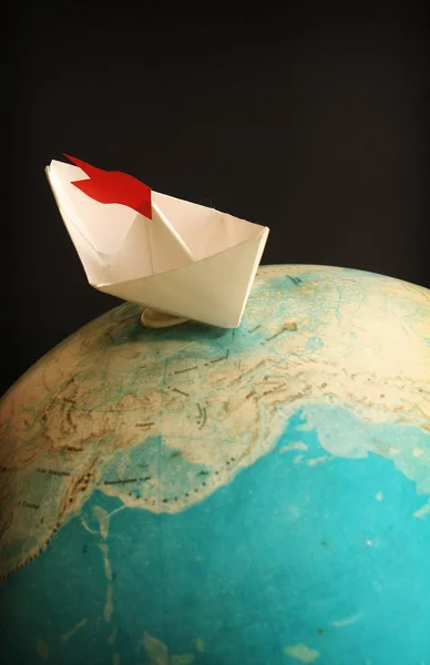 Travel concept with globe and paper boat