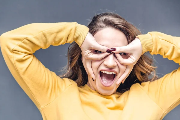 Young and attractive woman making funny face, studio portait on grey background — Stock Photo, Image