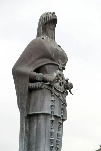 Escultura de bronce de una figura femenina estilizada sosteniendo un símbolo del rosario en el centro de Skopje —  Fotos de Stock