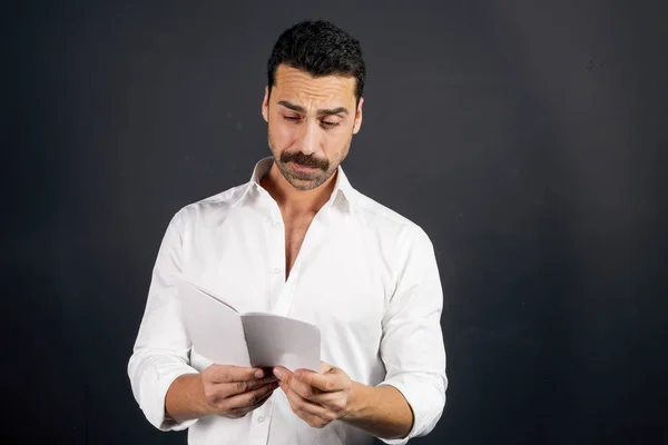 Joven con camisa blanca leyendo un folleto —  Fotos de Stock