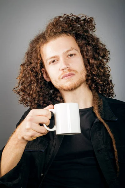 Young athletic ginger man holding a coffee mug, studio portrait