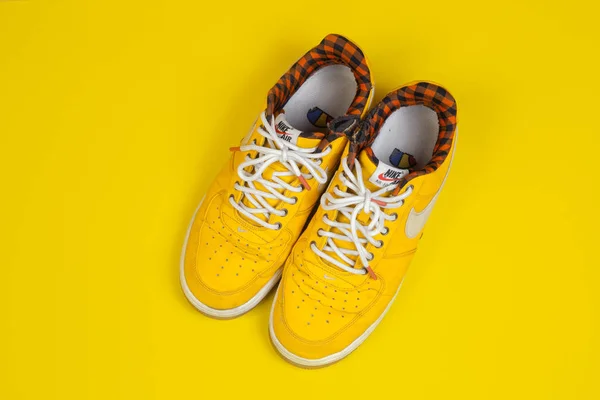 Used pair of Yellow Nike Air Force sneakers on yellow background — Stock Photo, Image