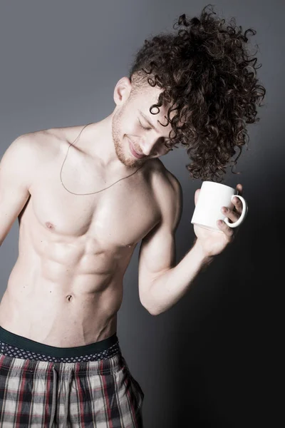 コーヒーや紅茶 スタジオ ポートレートの杯を持つ長い巻き毛を持つ魅力的な若い男 — ストック写真