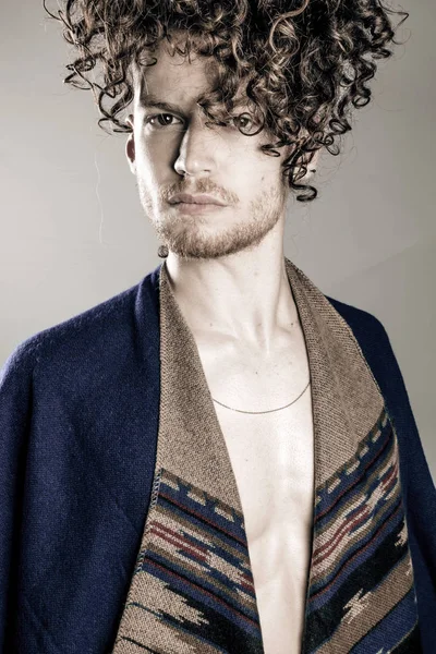 Young athletic ginger man in pancho studio portrait