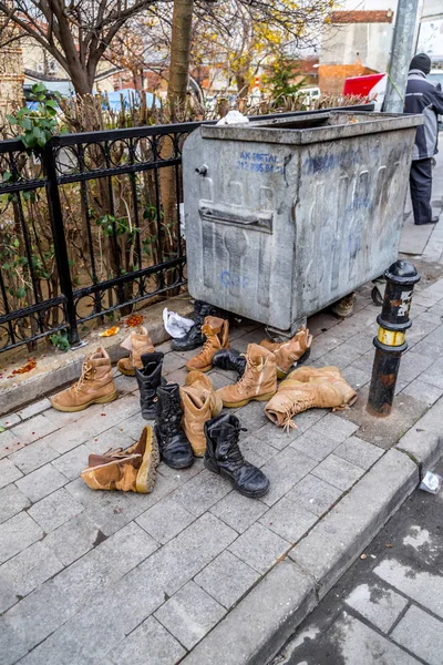 Old boots next to a garbage bin — Stock Photo, Image