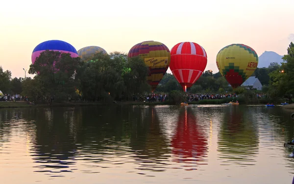 Воздушные шары, летящие в вечернем небе возле озера — стоковое фото