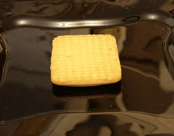 One cookie laying on the black plate — Stock Photo, Image