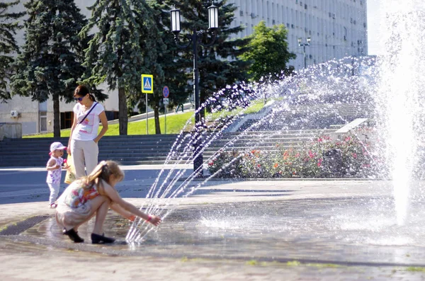 Children near a splashing fontain in the center of town — Stock Photo, Image