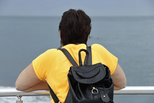 Vrouw met rugzak staande op de kust — Stockfoto