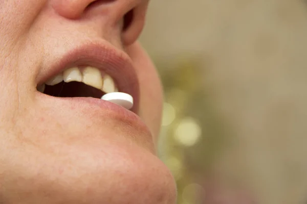 Female mouth with a white pill between the tooth — Stock Photo, Image