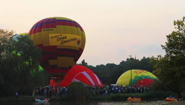 Balões de ar quente voando no céu da noite perto do lago — Fotografia de Stock