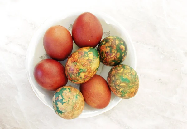 Барвисті великодні яйця на білій тарілці, розміщеній на мисці — стокове фото