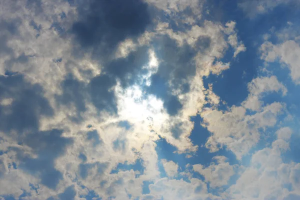 Stormachtige witte wolken op blauwe lucht en zon achter wolken — Stockfoto