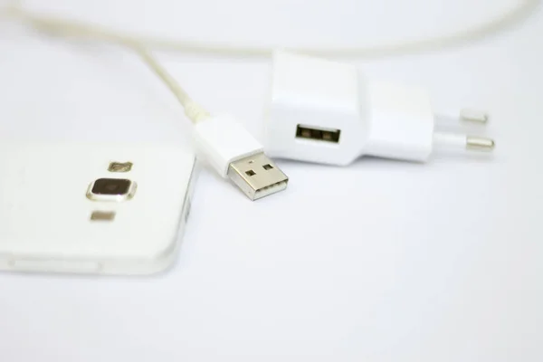白の背景に隔離された電源コードと現代の白いスマートフォンや携帯電話の充電 — ストック写真