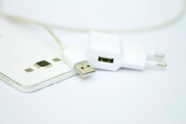Beyaz telefon ve telefon kablosu beyaz düzlükte izole edilmiş.