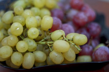 Kırmızı ve beyaz şarap. Siyah tabakta hazır üzüm var.