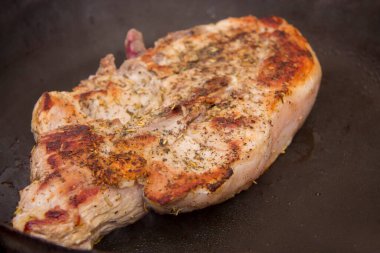 Mutfaktaki kızartma tavasında yarı pişmiş biftek.