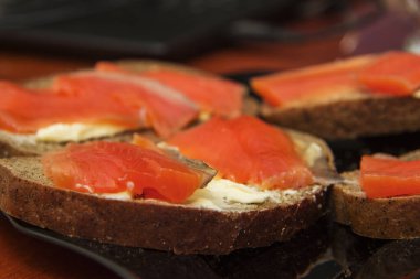 Taze somonlu sandviç, tuzlu somon balığı, tereyağı ve siyah tabakta siyah ekmek.