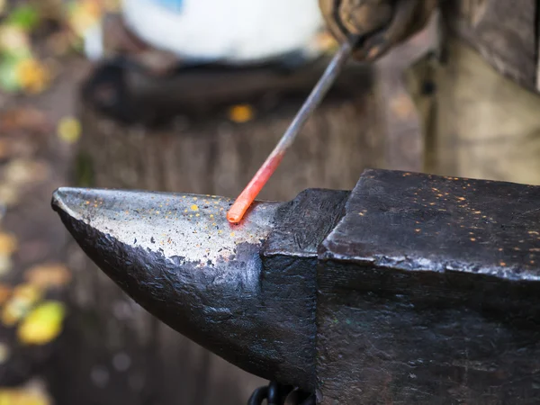 Red hot iron rod on anvil — Stock Photo, Image