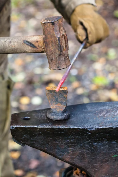 Blacksmith chops iron rod with hammer and chisel — Stock Photo, Image