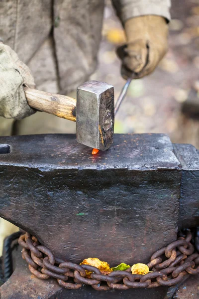 Ferreiro forja haste de ferro quente com marreta — Fotografia de Stock