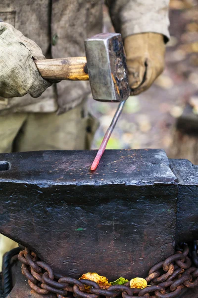 Blacksmith forges hot steel rod with sledgehammer — Stock Photo, Image