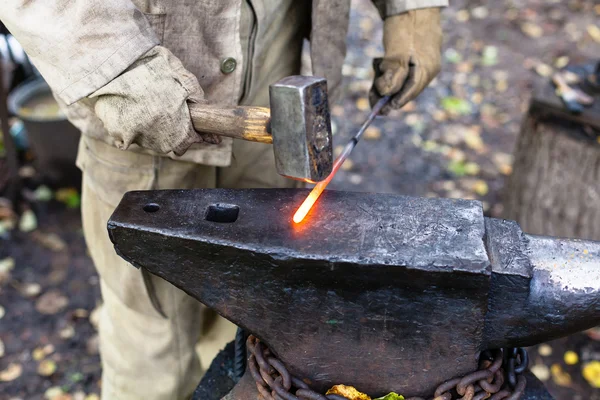 Blacksmith hammering hot steel rod on anvil — Stock Photo, Image
