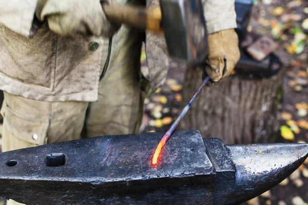 Blacksmith hammering red hot iron rod on anvil — Stock Photo, Image