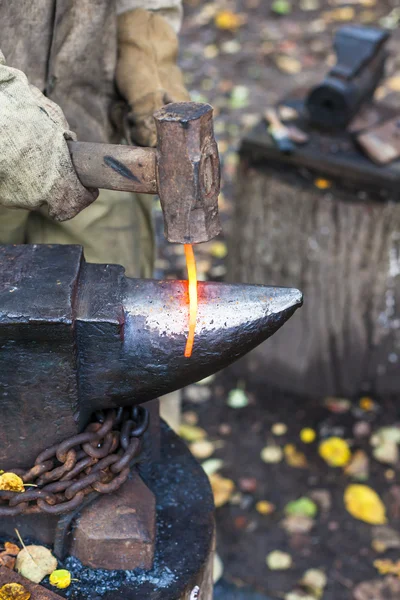 Blacksmith forges red glowing iron rod on anvil — Stock Photo, Image